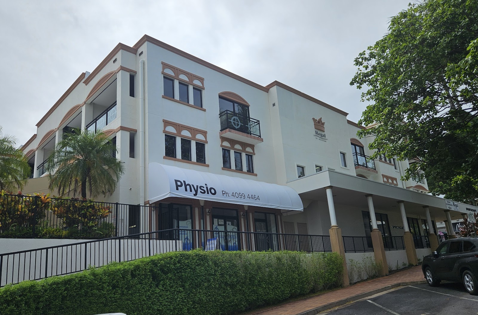 A clean white three storey commercial building with a physio clinic on the ground floor