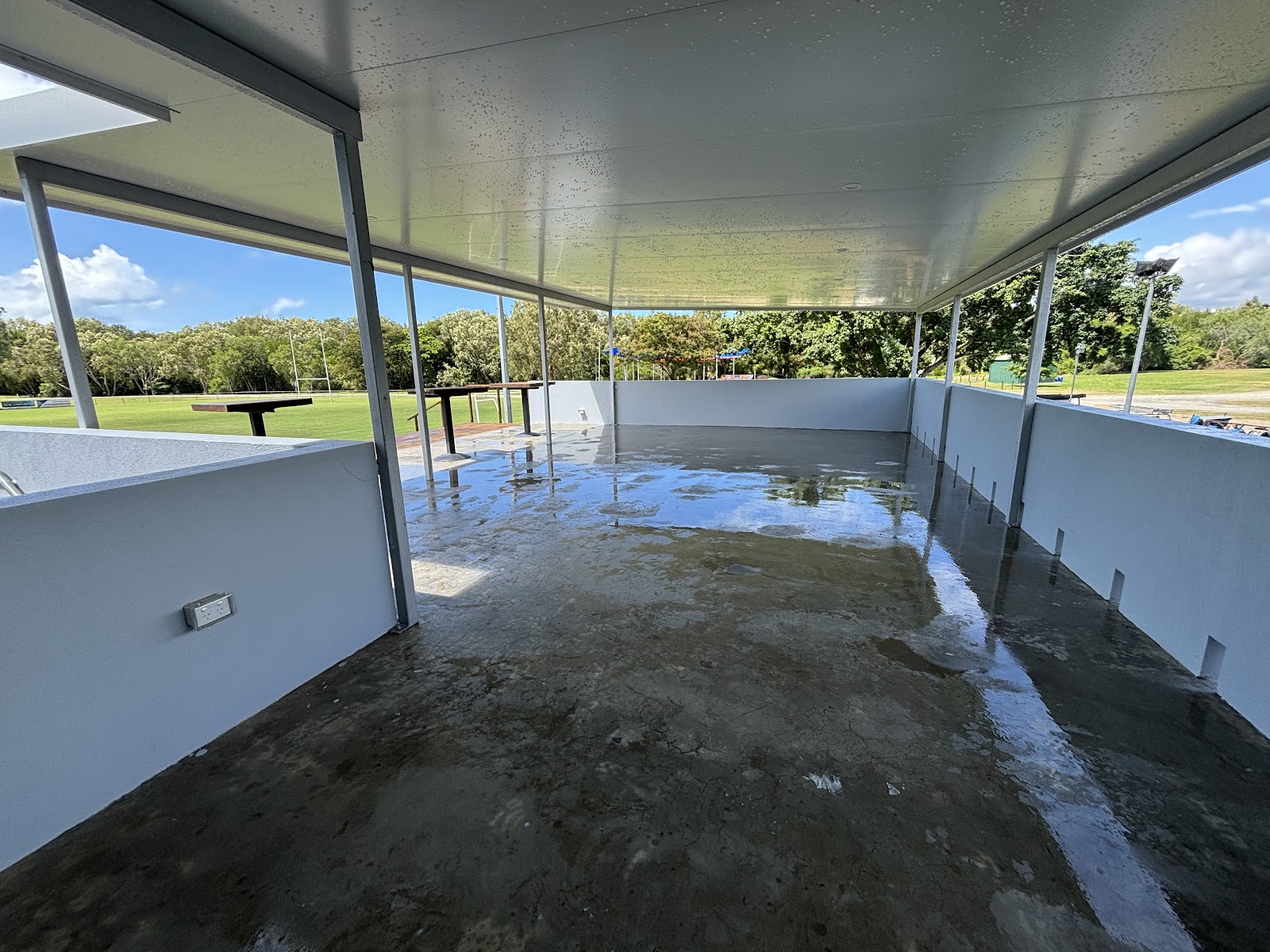 A covered patio mid-clean, wet concrete floor and freshly washed white walls